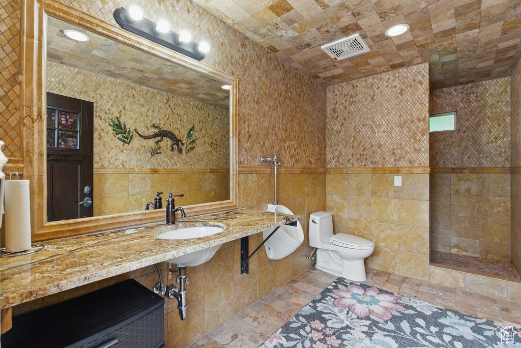 Bathroom featuring tile walls, toilet, and a sink