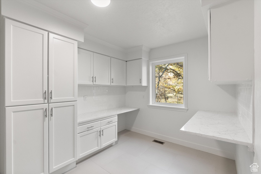 Mudroom featuring crown molding, built in study area, visible vents, and baseboards