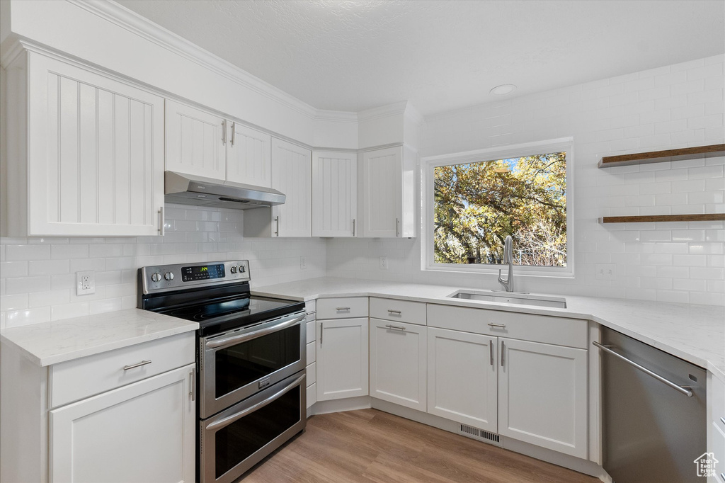 Kitchen with a sink, visible vents, backsplash, under cabinet range hood, and appliances with stainless steel finishes