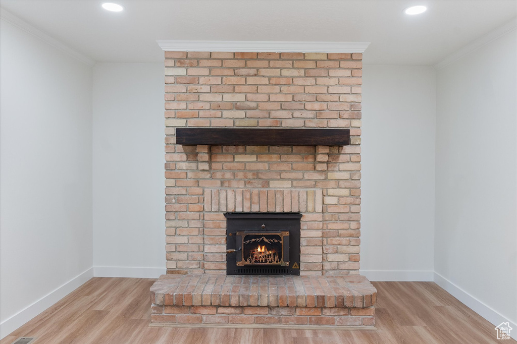 Interior details with baseboards, a brick fireplace, crown molding, and wood finished floors