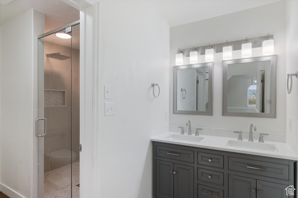 Bathroom featuring a shower stall, double vanity, and a sink