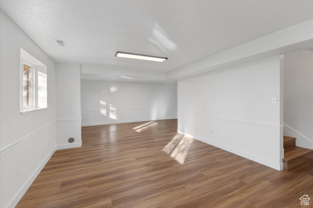 Spare room featuring wood finished floors, visible vents, baseboards, and stairs