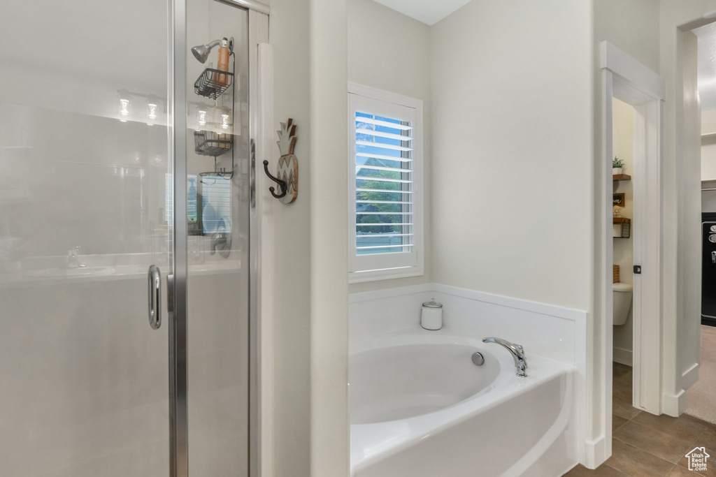 Bathroom with a stall shower, a garden tub, tile patterned flooring, and toilet