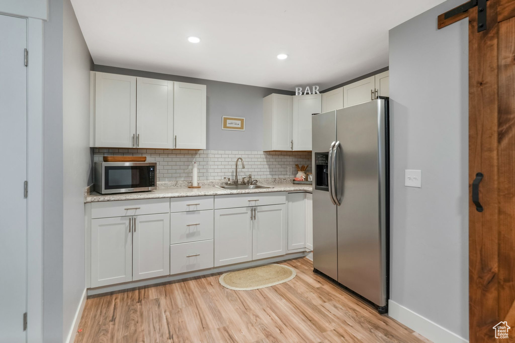Kitchen featuring stainless steel appliances, a sink, light wood-style floors, tasteful backsplash, and recessed lighting