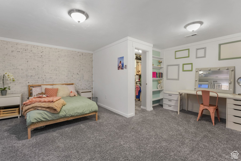 Carpeted bedroom with crown molding, an office area, brick wall, and baseboards