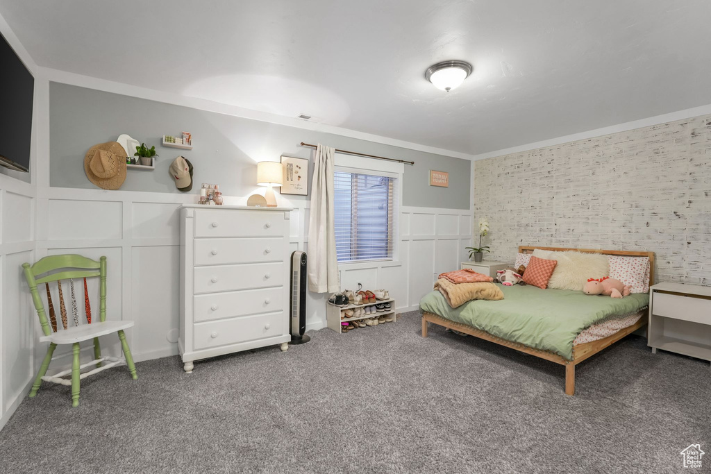 Bedroom featuring a decorative wall, wainscoting, carpet floors, and ornamental molding