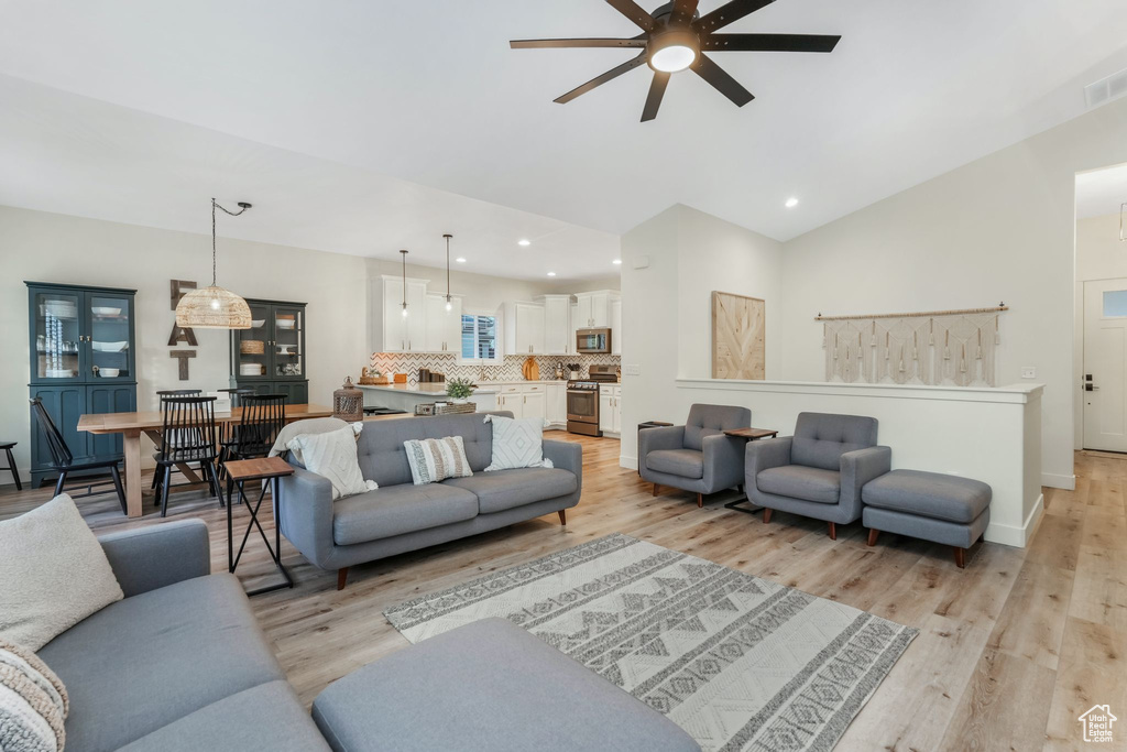 Living area featuring a ceiling fan, light wood-style flooring, high vaulted ceiling, recessed lighting, and baseboards