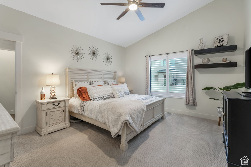 Bedroom featuring light colored carpet, baseboards, vaulted ceiling, and ceiling fan