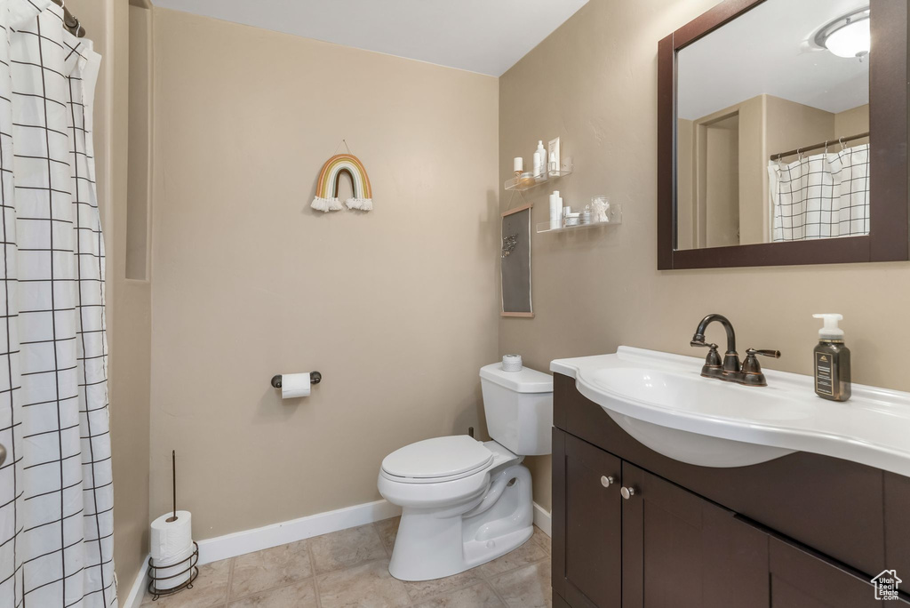 Bathroom with toilet, baseboards, vanity, a shower with curtain, and tile patterned floors