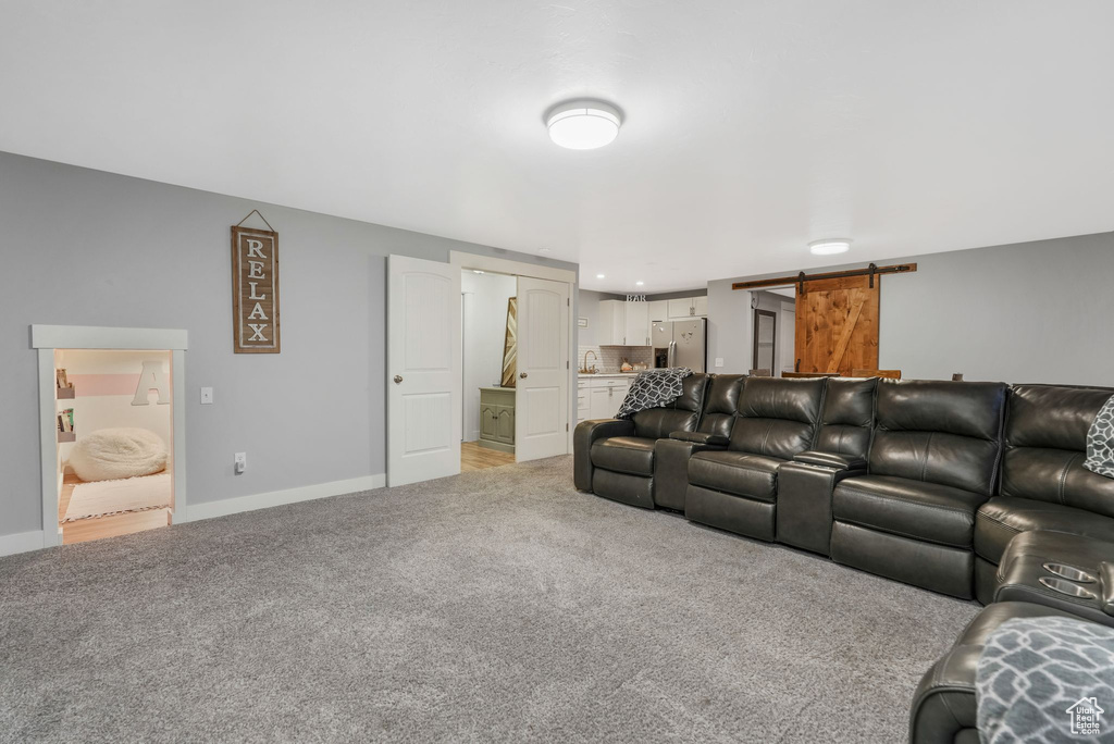 Living room with a barn door, light carpet, and baseboards