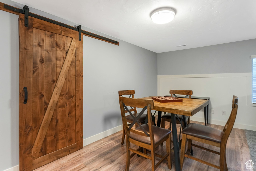 Dining room with a barn door, wood finished floors, and baseboards