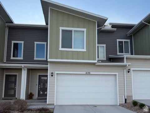 View of property featuring board and batten siding, driveway, and an attached garage