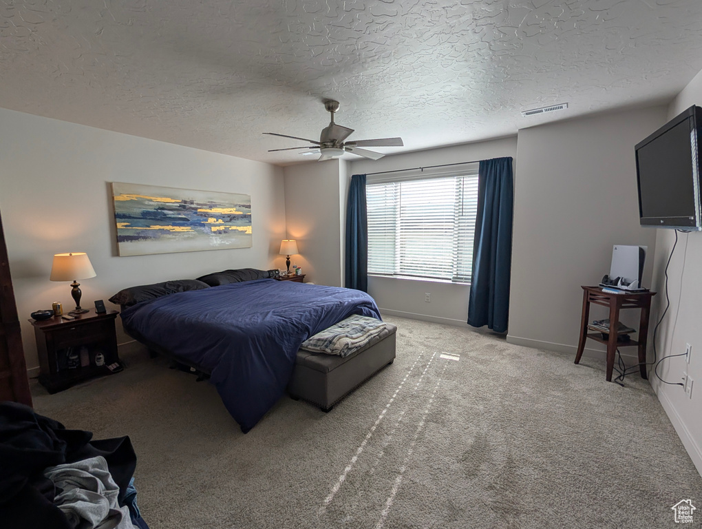 Bedroom featuring light colored carpet, baseboards, a textured ceiling, and a ceiling fan