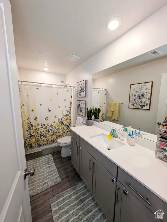 Full bathroom featuring wood finished floors, toilet, vanity, and shower / bath combo with shower curtain