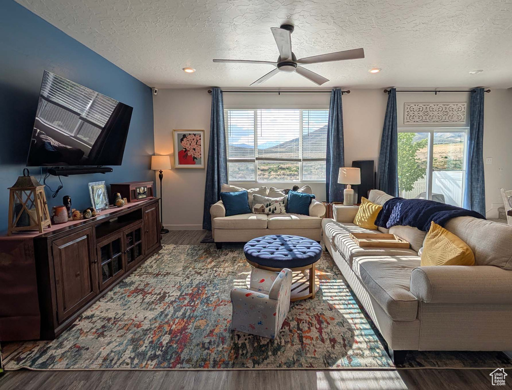 Living area with a textured ceiling, ceiling fan, wood finished floors, recessed lighting, and baseboards