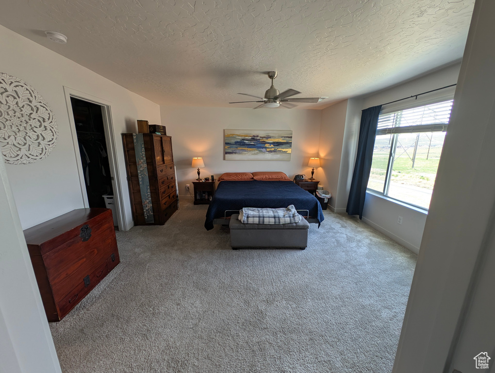 Carpeted bedroom with a textured ceiling, a ceiling fan, and baseboards