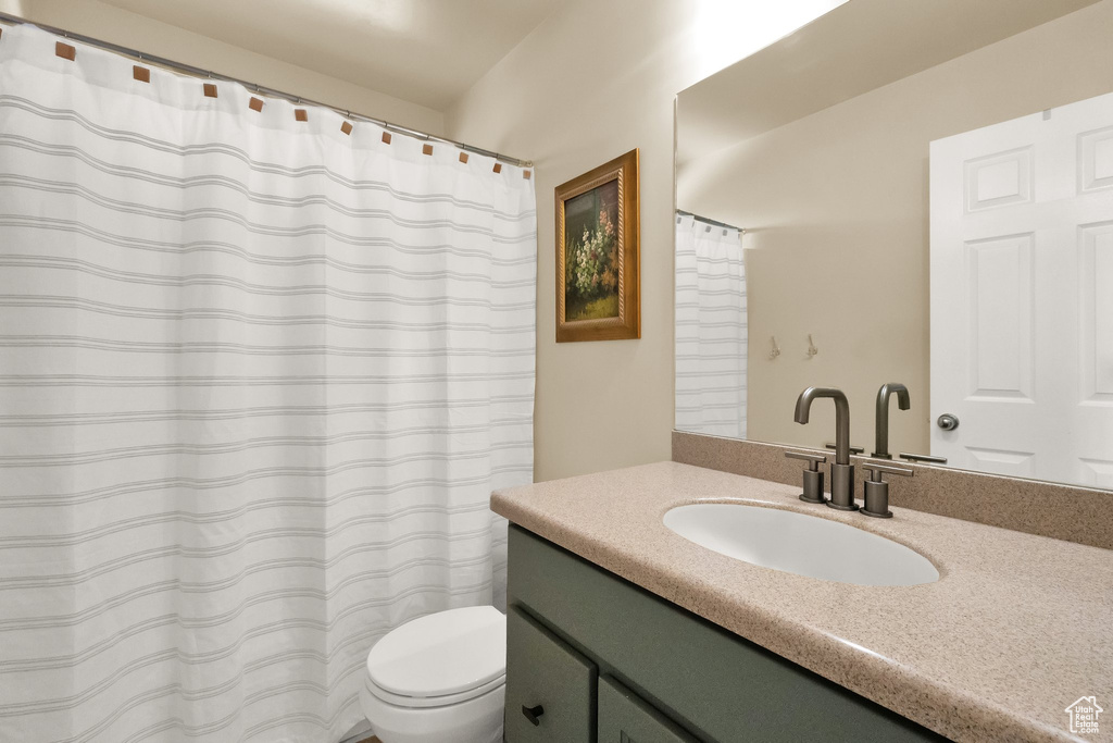 Bathroom with vanity, a shower with shower curtain, and toilet