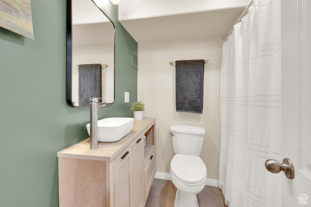Bathroom featuring toilet, vanity, visible vents, and baseboards