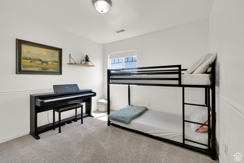 Bedroom with wainscoting, carpet flooring, and visible vents
