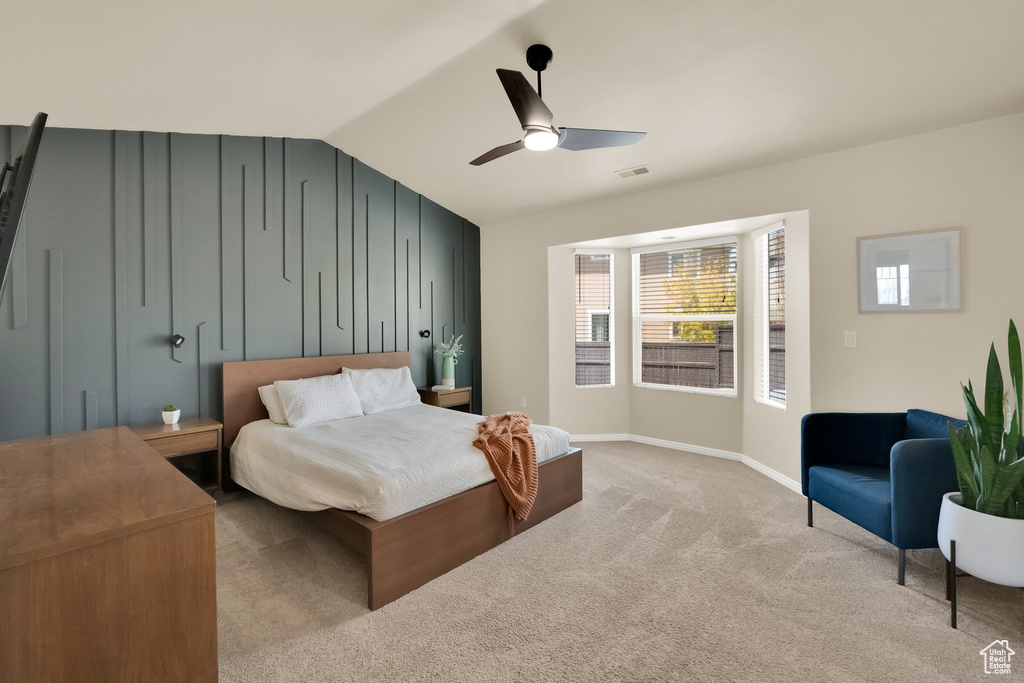 Bedroom featuring vaulted ceiling, visible vents, a ceiling fan, baseboards, and light colored carpet