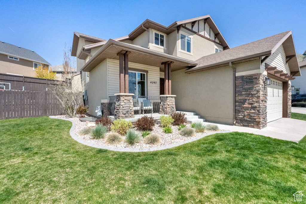 Craftsman-style house with fence, a front lawn, stucco siding, a porch, and stone siding