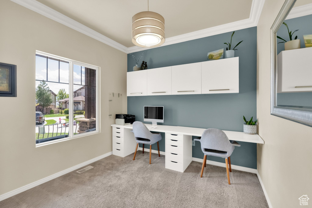 Office area featuring visible vents, built in desk, light colored carpet, and crown molding