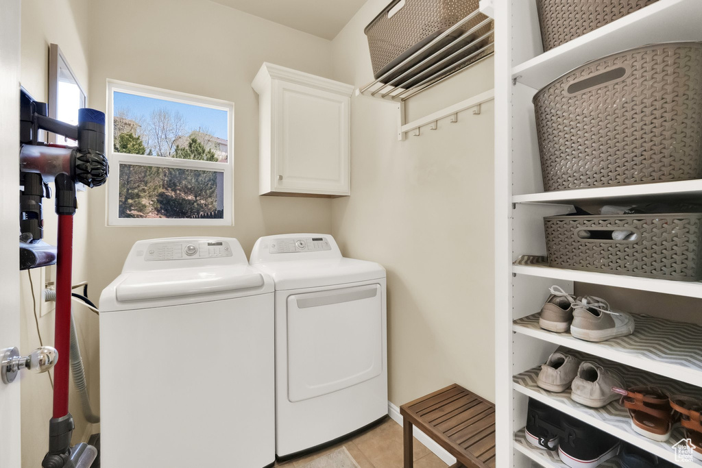 Laundry room featuring cabinet space, light tile patterned floors, and washer and clothes dryer