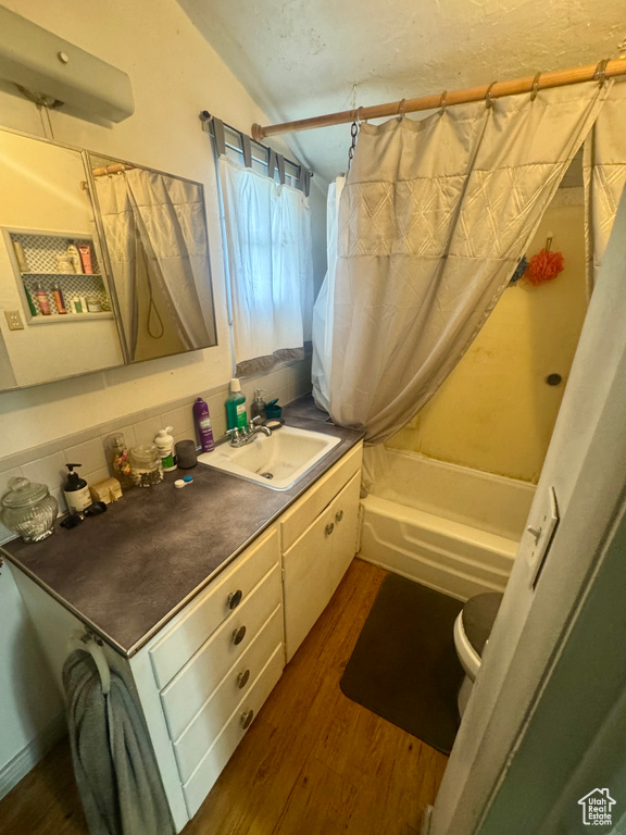Full bath with vanity, shower / bath combination with curtain, and wood finished floors