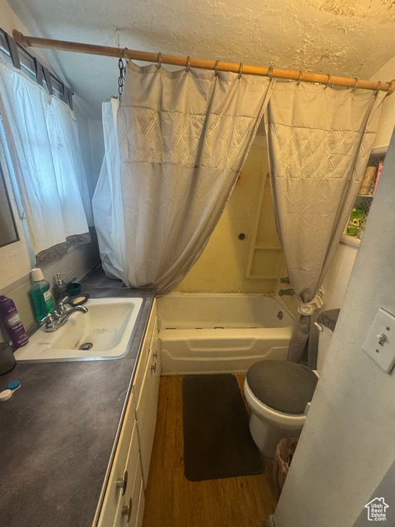 Bathroom with toilet, shower / tub combo with curtain, wood finished floors, and vanity
