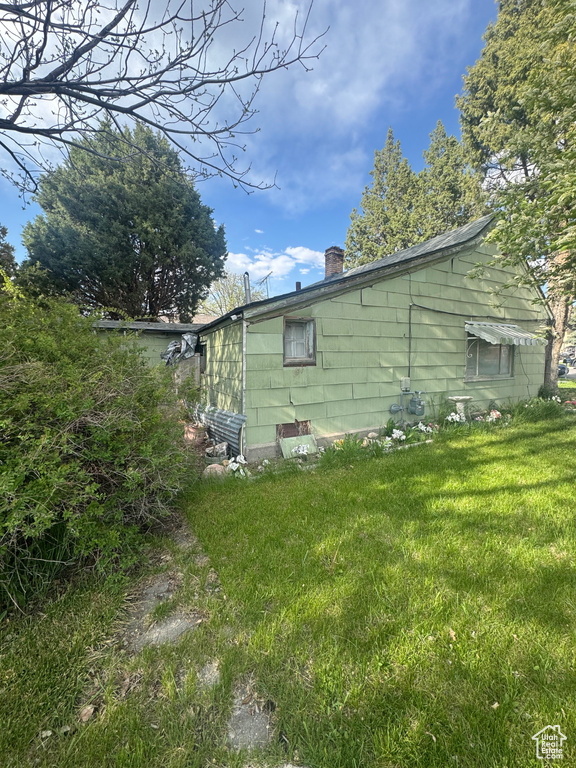 View of side of property featuring a yard and a chimney