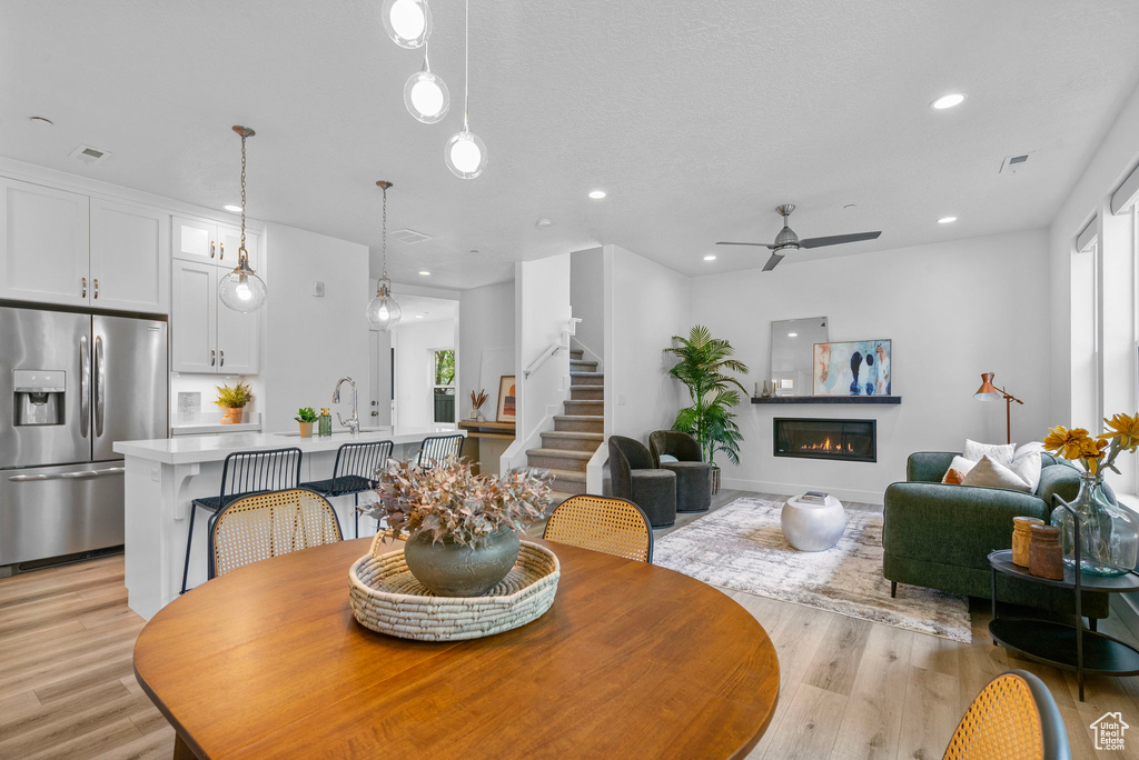 Dining room featuring light wood finished floors, a glass covered fireplace, healthy amount of natural light, and recessed lighting