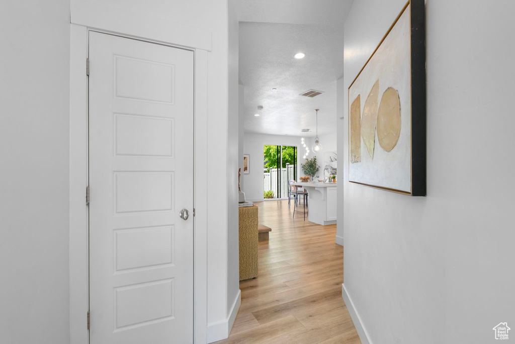 Hall featuring baseboards, light wood-type flooring, and recessed lighting