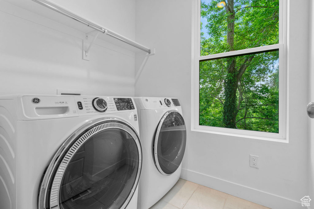 Laundry room with separate washer and dryer, light tile patterned floors, and baseboards