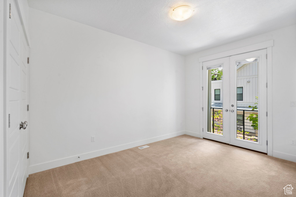 Unfurnished room with light carpet, baseboards, and french doors