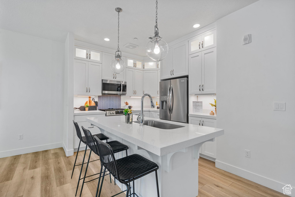Kitchen with stainless steel appliances, a sink, light countertops, baseboards, and a breakfast bar