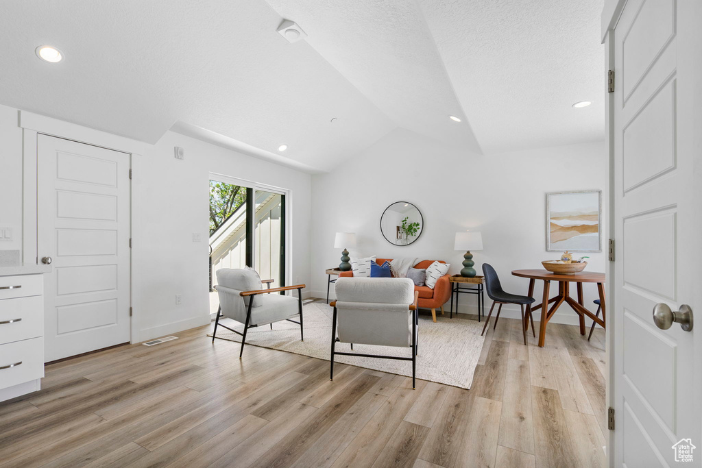 Living area featuring vaulted ceiling, light wood-style floors, baseboards, and recessed lighting