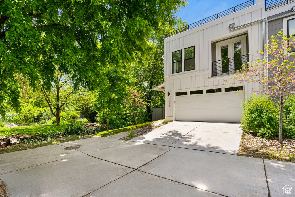 View of front facade with board and batten siding, driveway, and an attached garage