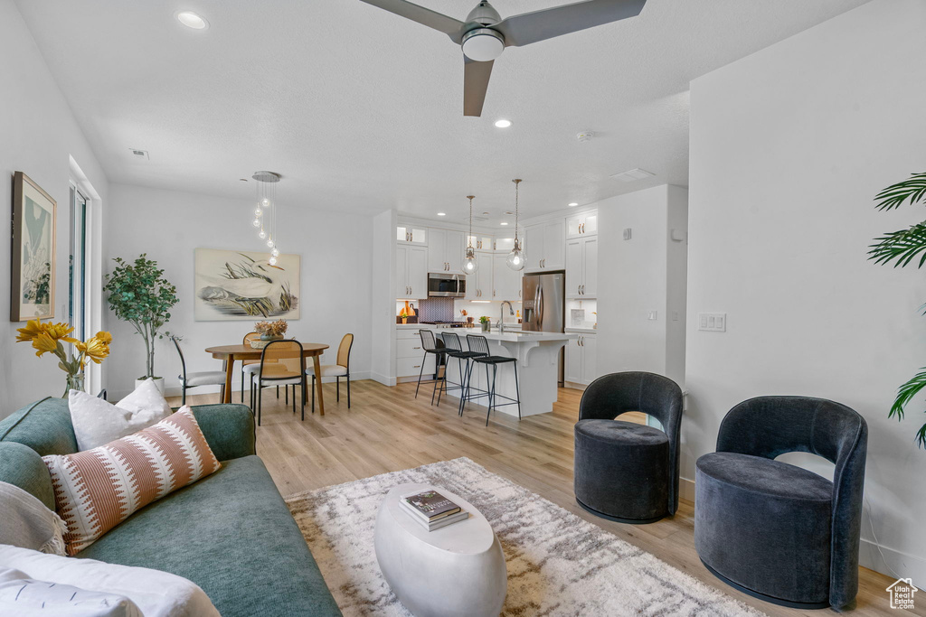 Living area with light wood-type flooring, recessed lighting, ceiling fan, and baseboards