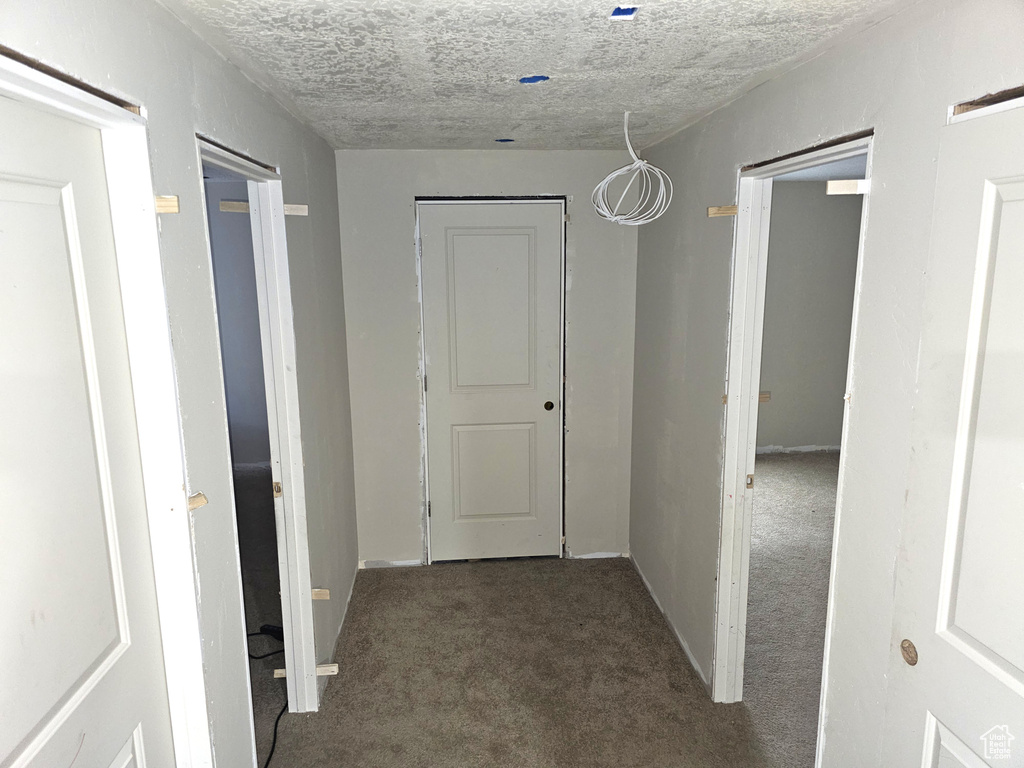 Corridor with carpet, a textured ceiling, and baseboards