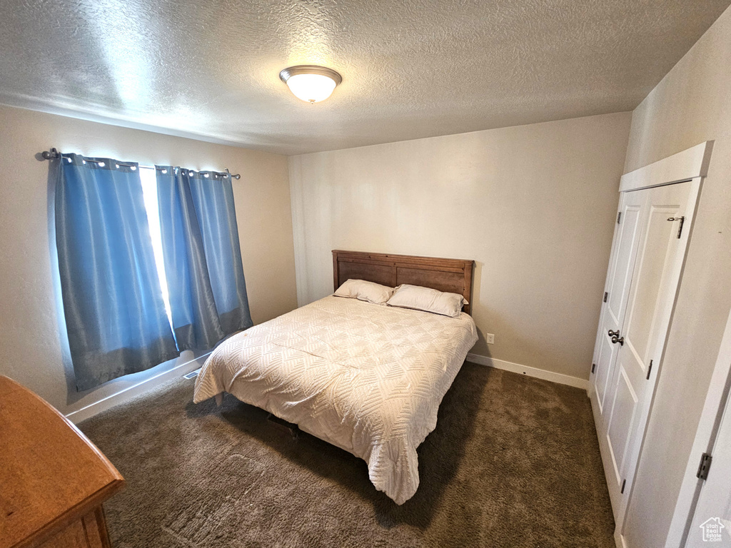 Carpeted bedroom with a textured ceiling and baseboards