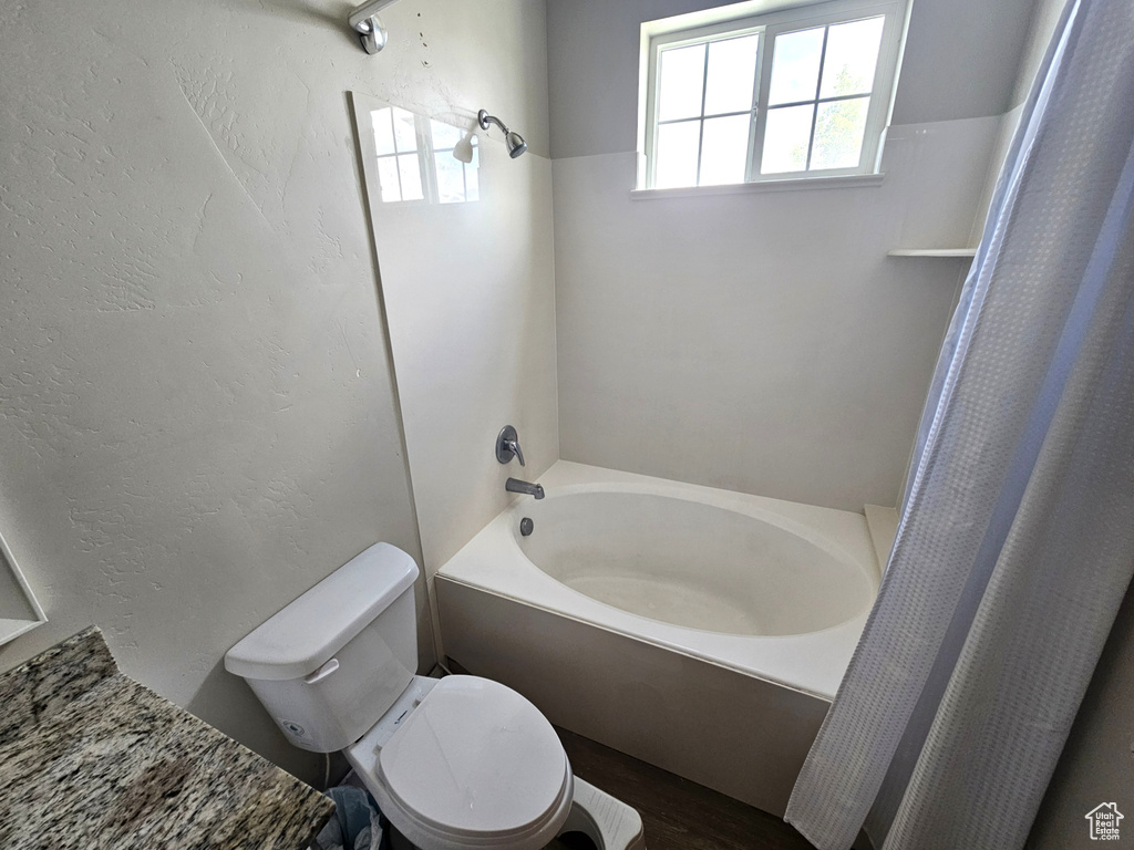 Full bath with toilet, a bath, a shower with shower curtain, and wood finished floors