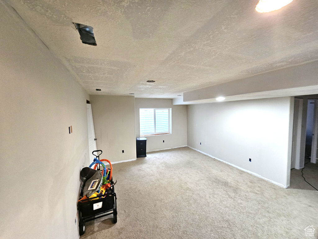Below grade area with a textured ceiling, carpet, and baseboards