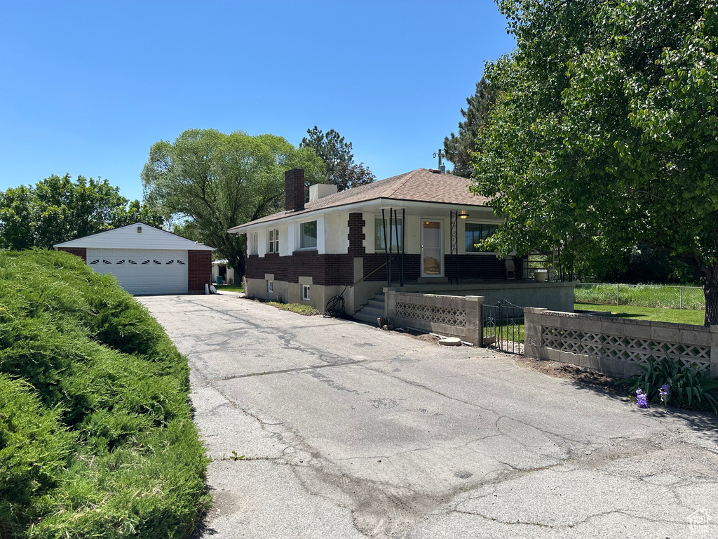 View of front of home featuring a garage, a porch, an outdoor structure, and a chimney