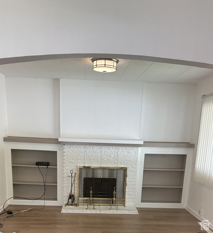 Detailed view of wood finished floors, built in features, a fireplace, and baseboards