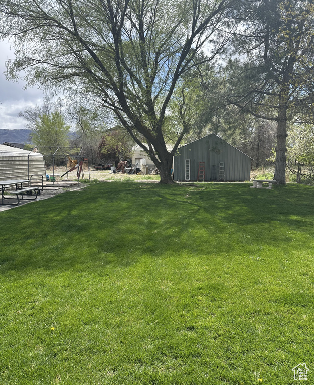 View of green lawn featuring a pole building and an outdoor structure