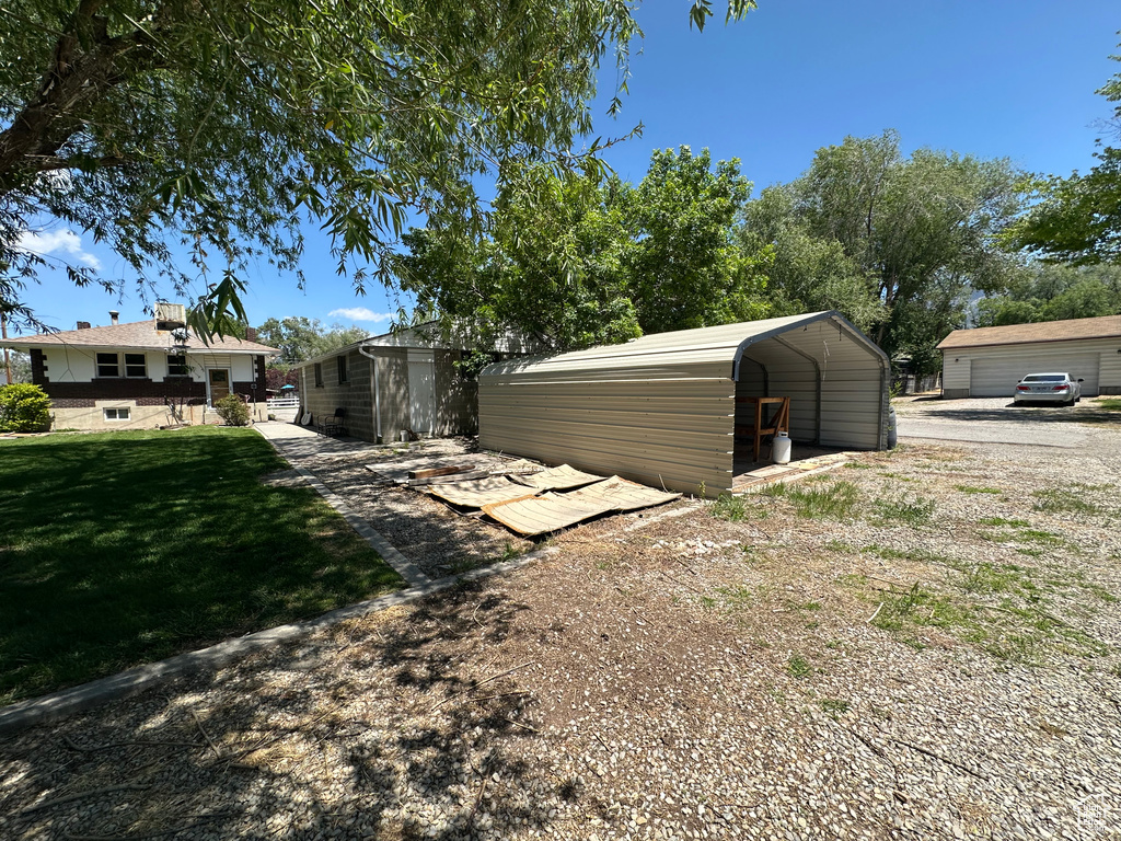 View of grassy yard with a detached carport and driveway