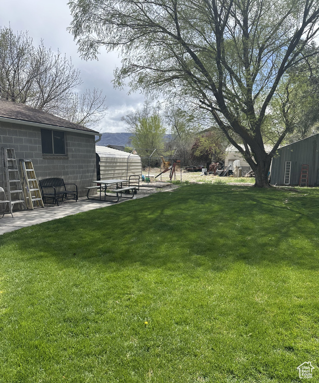 View of grassy yard featuring a patio