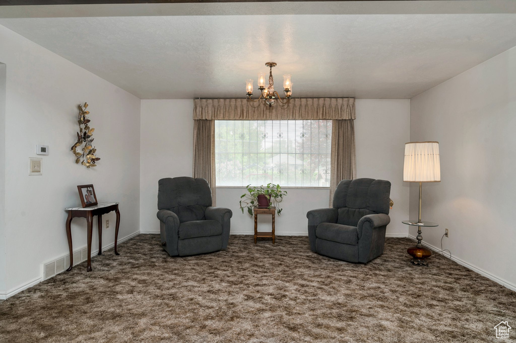 Sitting room with a chandelier, carpet floors, and baseboards