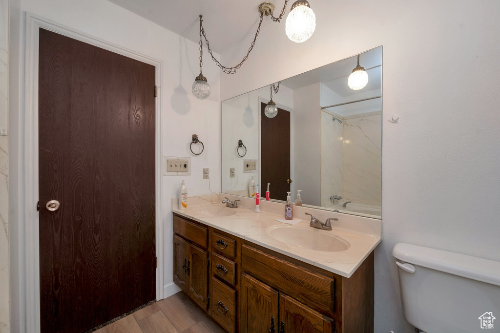 Full bath featuring toilet, double vanity, and wood finished floors