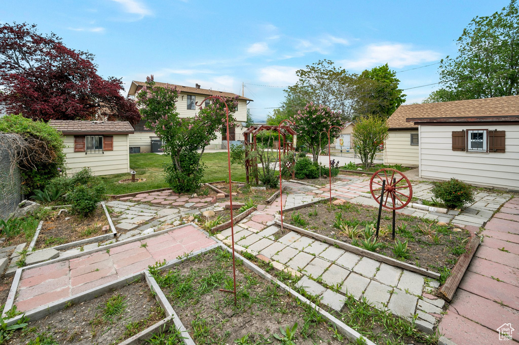 View of grassy yard with a vegetable garden and an outbuilding